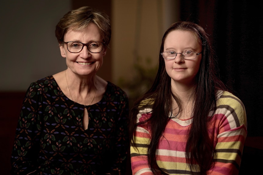 Two women, a mother and daughter, both wear glasses and smile.