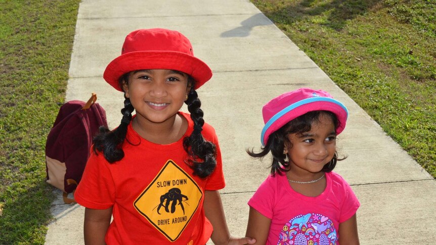 Two young girls wear t-shirts and hats.