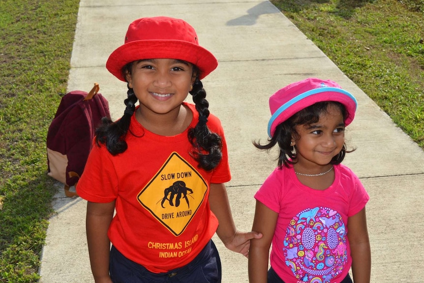 Two young girls wear t-shirts and hats.