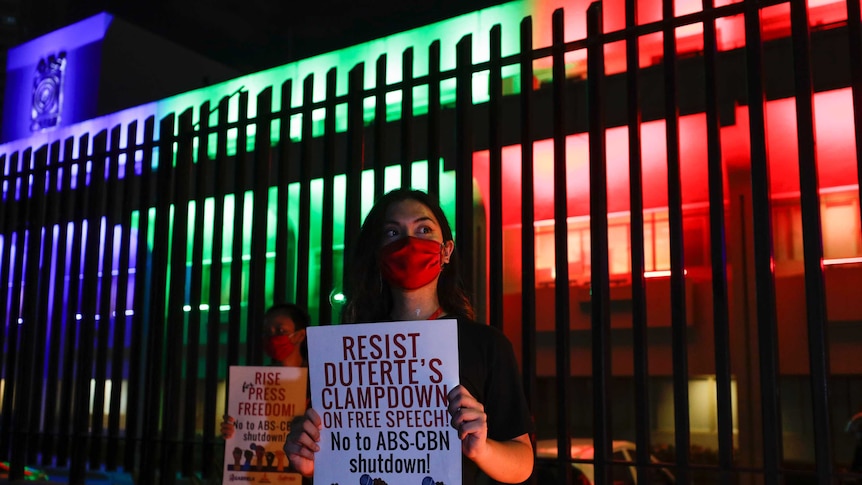 A woman holds a sign reading 'resist Duterte's clampdown'