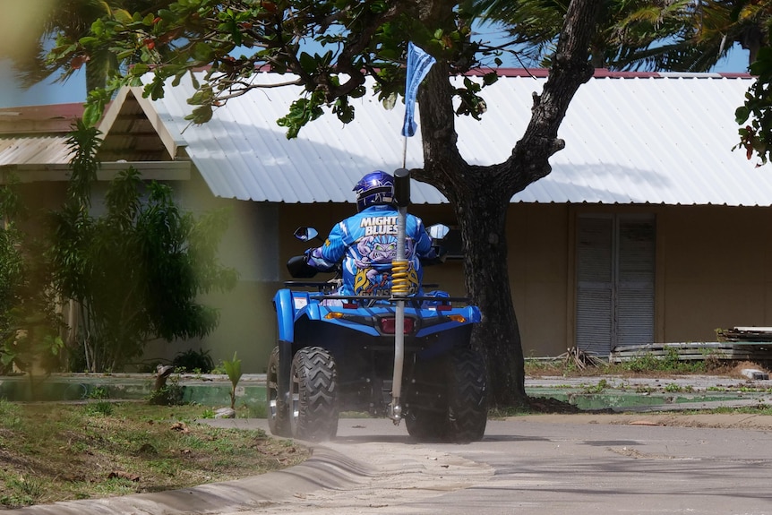 Man on a blue quad bike with a blues state of origin shirt and flag.