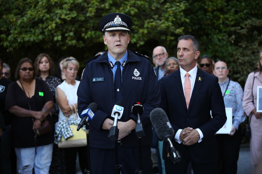 Victims stand behind the police minister and commissioner at a press conference