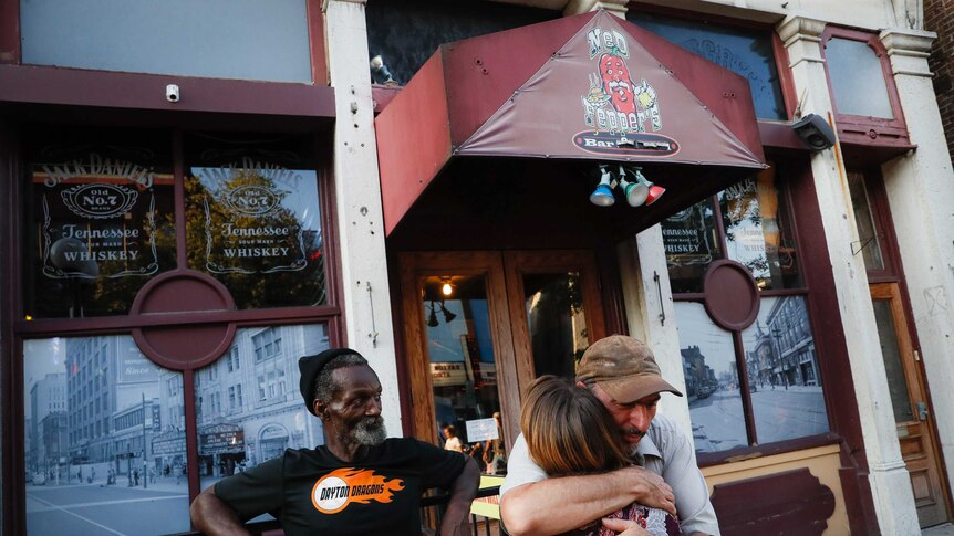 Mourners hug at the front of Ned Peppers bar.