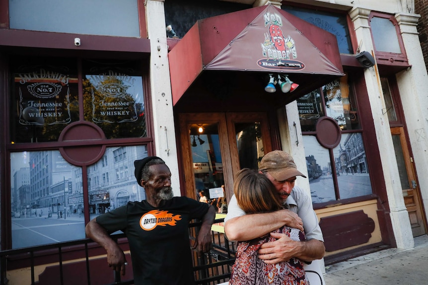 Mourners hug at the front of Ned Peppers bar.