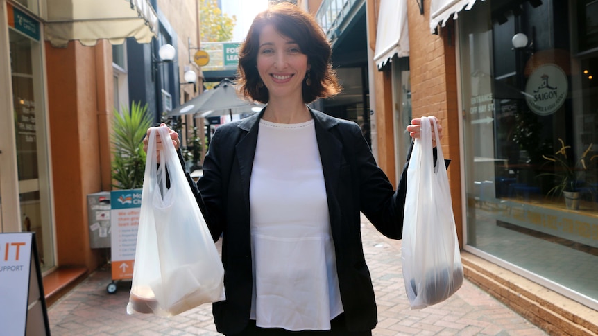 City of Perth Councillor Jemma Green stands holding plastic bags in an alley.
