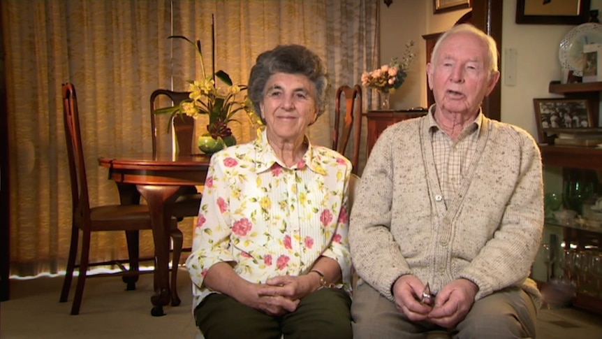 An elderly couple sit in their living room