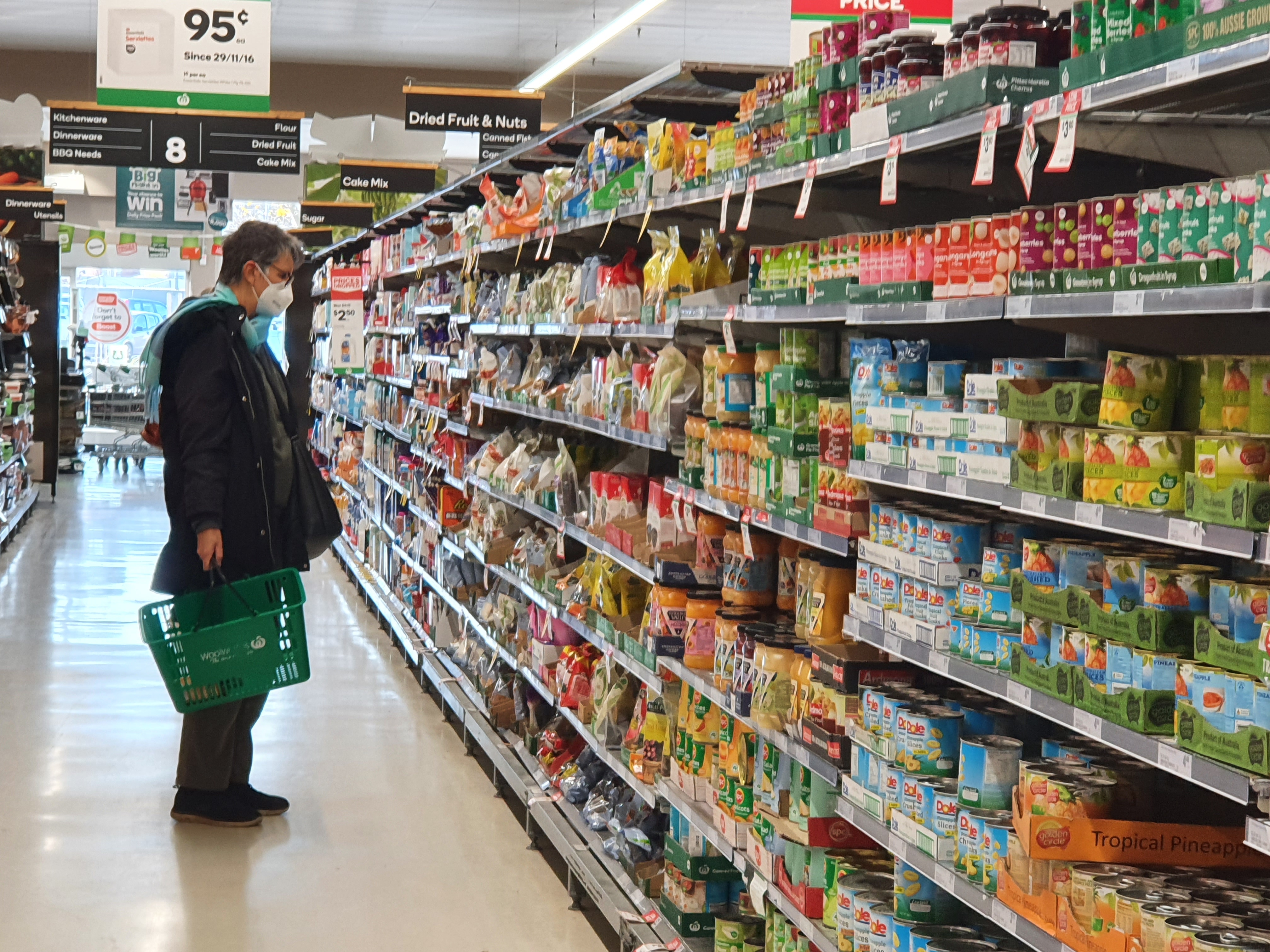 Woman in mask shopping in Woolworths packaged food aisle June 28