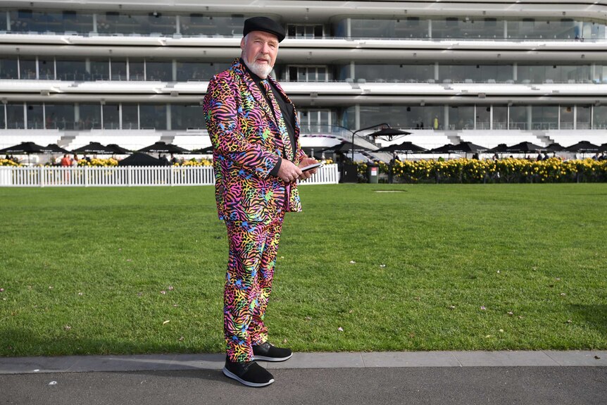 A man dressed in a colourful leopard print suit and matching tie at Flemington Racecourse.