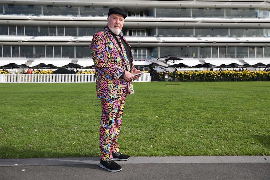 A man dressed in a colourful leopard print suit and matching tie at Flemington Racecourse.