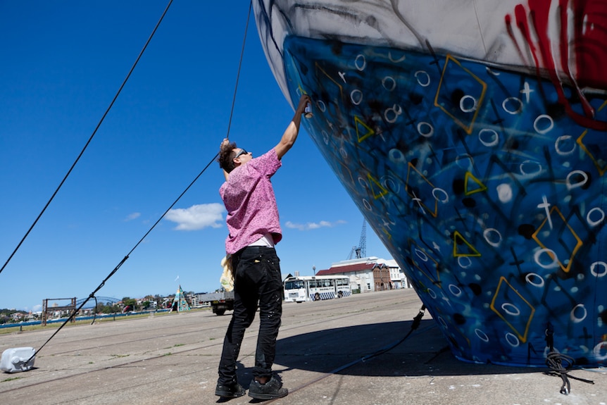 Street artist Anthony Lister at work on Sydney's Cockatoo Island as part of the Outpost street art festival.