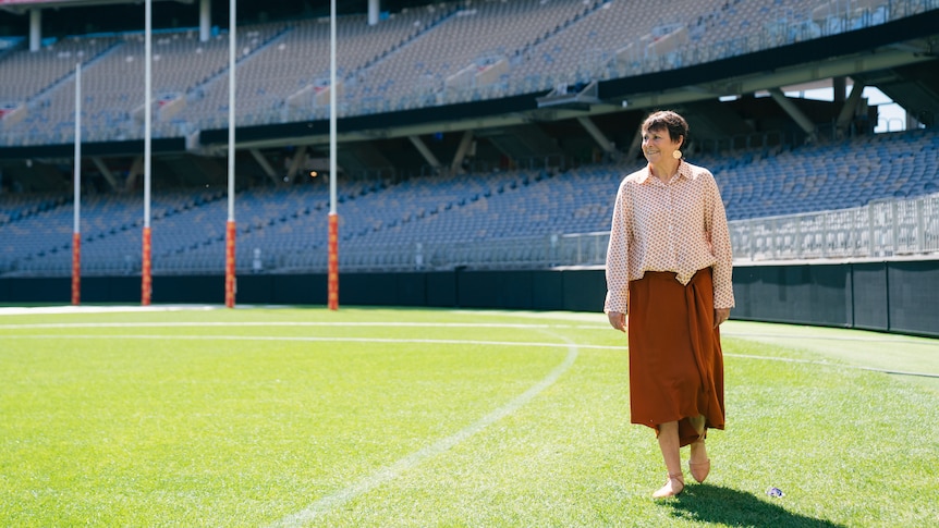 Jan Cooper walking across a football field.