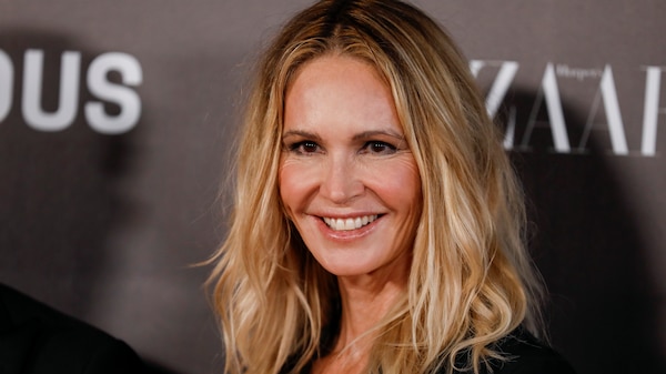 Woman with blonde wavy hair smiles at cameras
