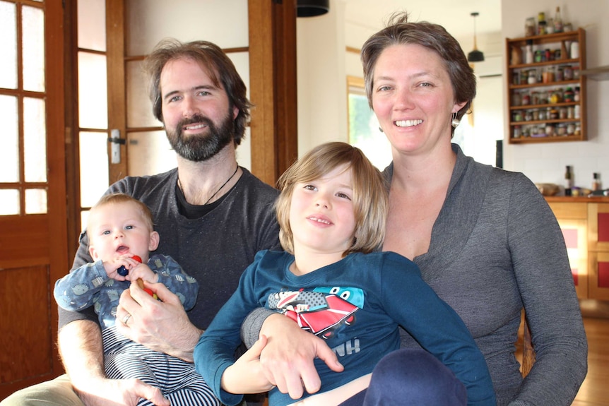 A man holding a baby and a woman with a child on her lap.