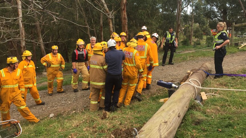 Rescue workers stretcher Odie Barwick from the scene, where he was trapped under a telegraph pole.