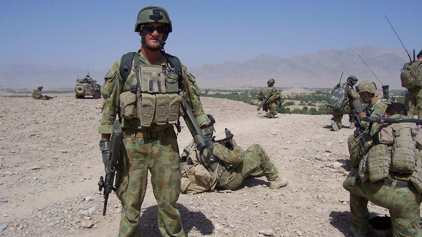 A soldier in Afghanistan wearing army uniform and holding a weapon.