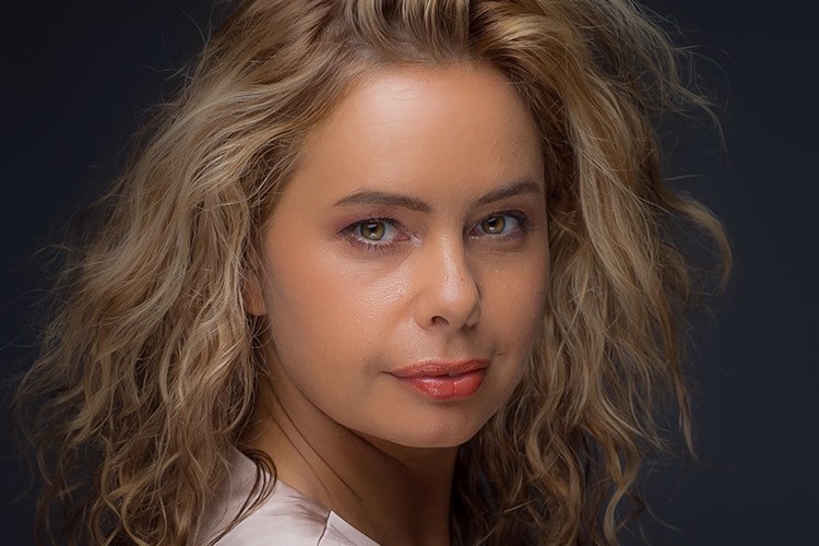 A young indigenous woman with brown curly hair with a serious look on her face.