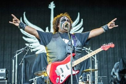 A guitar player holds his arms out while performing on stage.