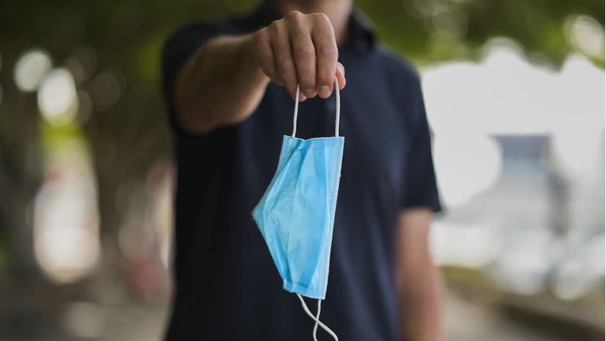 Person holding a face mask and about to drop it.