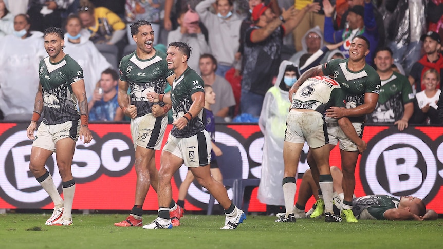 Maori NRL All Stars players smile and yell in the rain after beating the Indigenous All Stars.