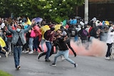 A man throws an object towards police as protesters clash with authorities in the street.