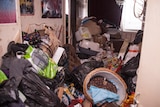A hallway of a house blocked with piles and piles of clutter.