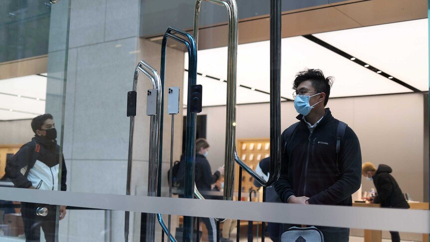 A customer wearing a protective mask looks at an iPhone in a Sydney store.