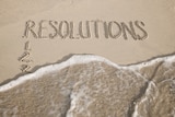 New Year Resolutions listed in the sand get wiped away by a swift wave