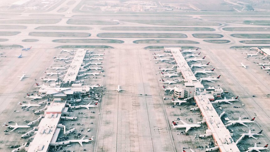 Planes wait at gates in an aerial panorama of an airport