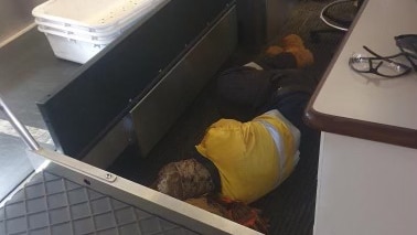 Man in high vis sleeping next to a baggage conveyor