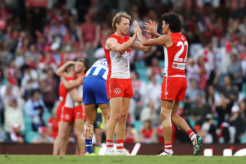 Callum Mills and Justin McInerney high-five each other in the middle of the ground