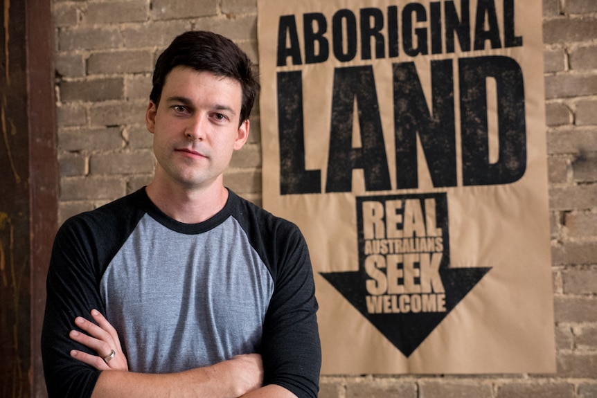 Peter Drew in front of his Real Australians Seek Welcome poster.