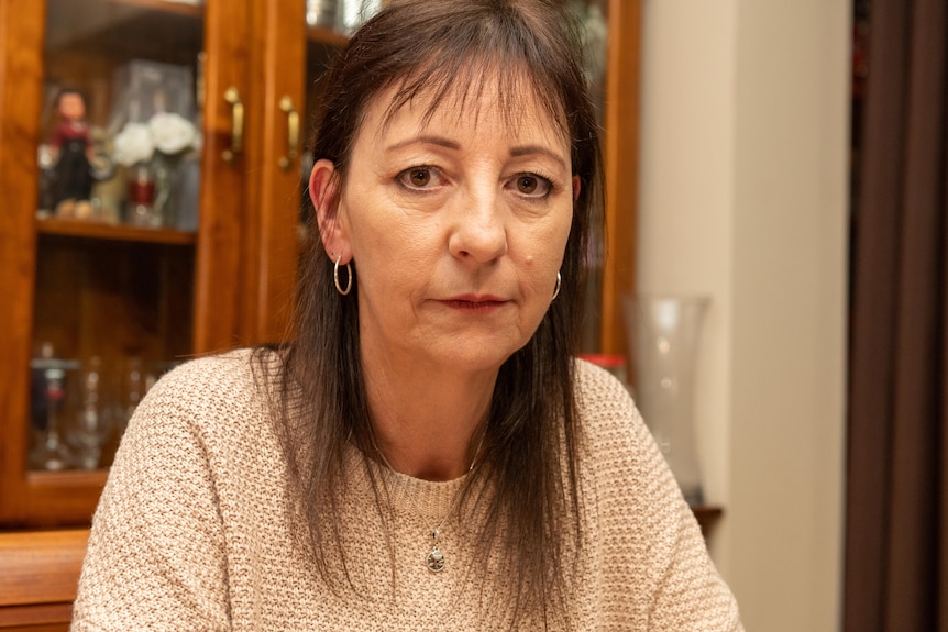 Woman with brown hair wearing a beige jumper.