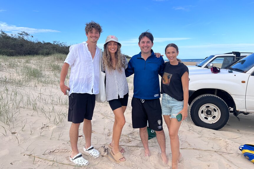 two men and two women standing in sand at the beach on K'gari Fraser Island