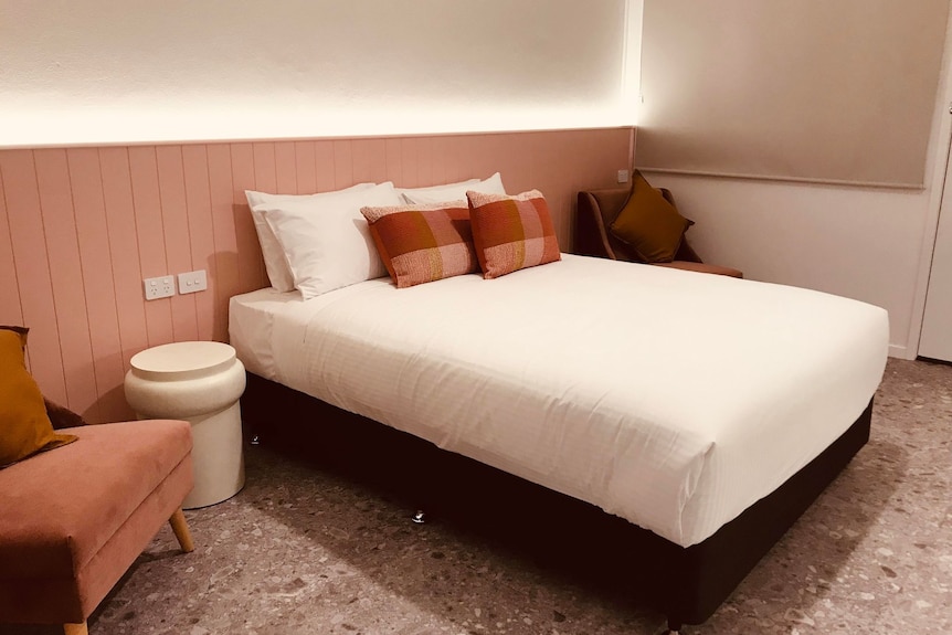 Hotel room with white and pink walls and a double bed. 