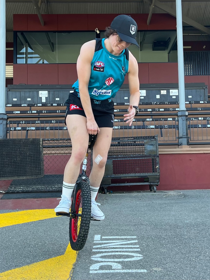 Ebony O'Dea performs a unicycle trick at Port Adelaide training at Alberton