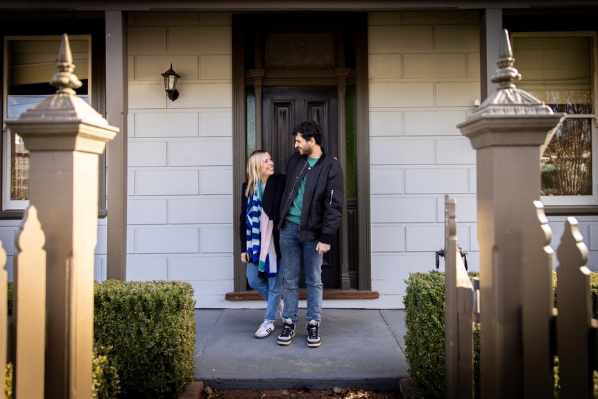 A man and woman standing in front of a house