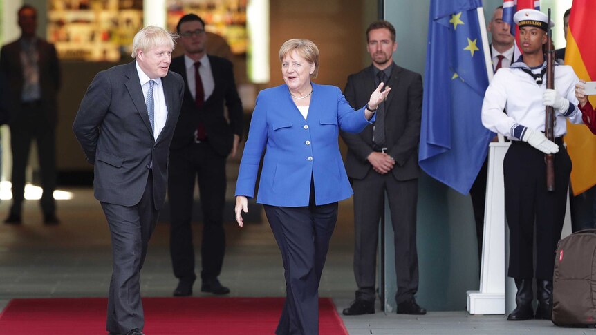 German Chancellor Angela Merkel welcomes Britain's Prime Minister Boris Johnson in front of EU and British flags.