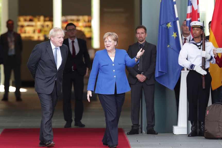 German Chancellor Angela Merkel welcomes Britain's Prime Minister Boris Johnson in front of EU and British flags.