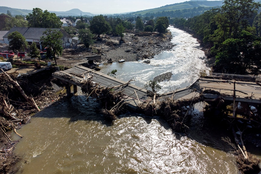 A bridge destroyed by flooding lays in a river