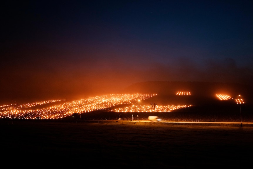 Fires burn on a hillside with a van travelling from right to left in front