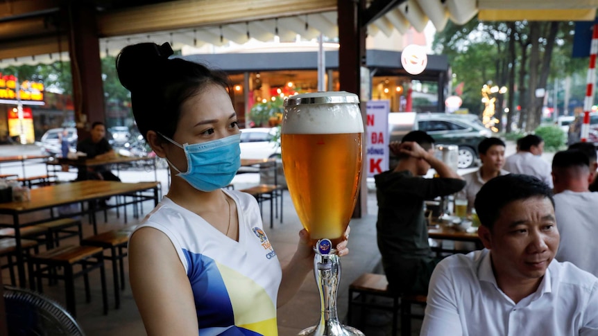 A woman serves beer at a bar and restaurant in Hanoi.