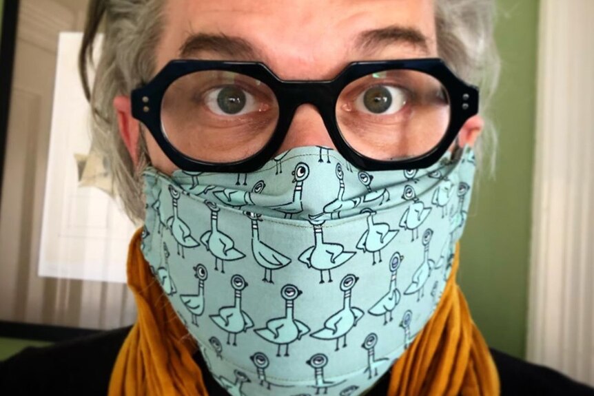 Close headshot of Mo Willems wearing black spectacles and a face mask during the coronavirus pandemic.