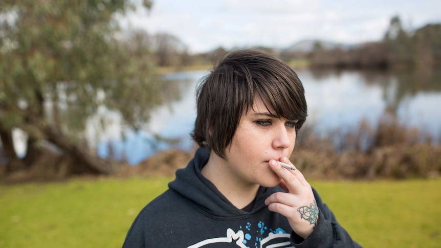 Erin Dumesny smokes a cigarette in a park.