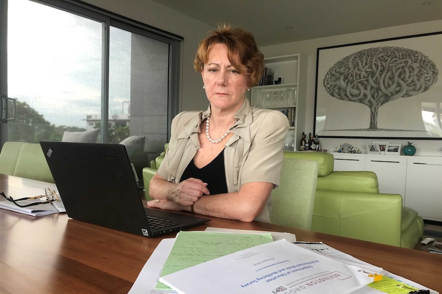 A woman sits at a laptop in an office