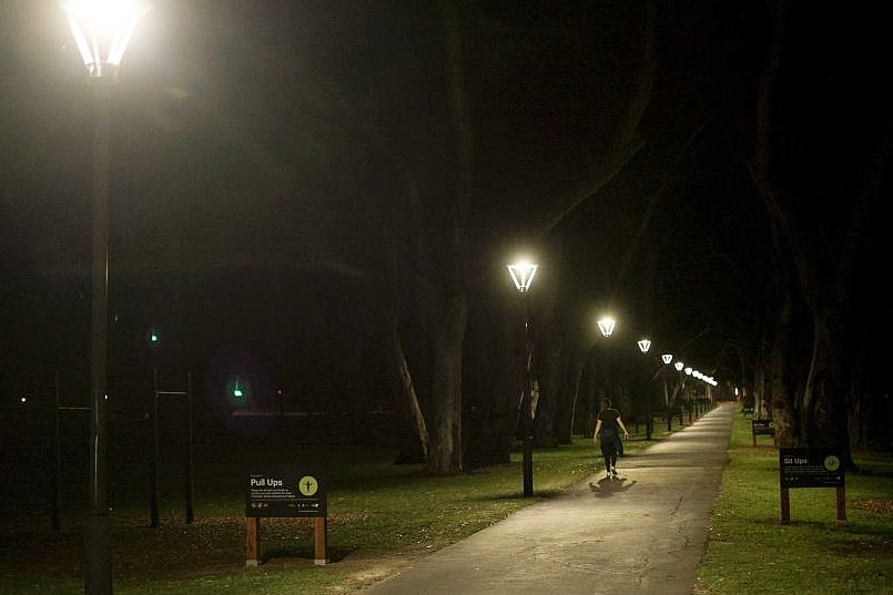 a woman walking through a park at night