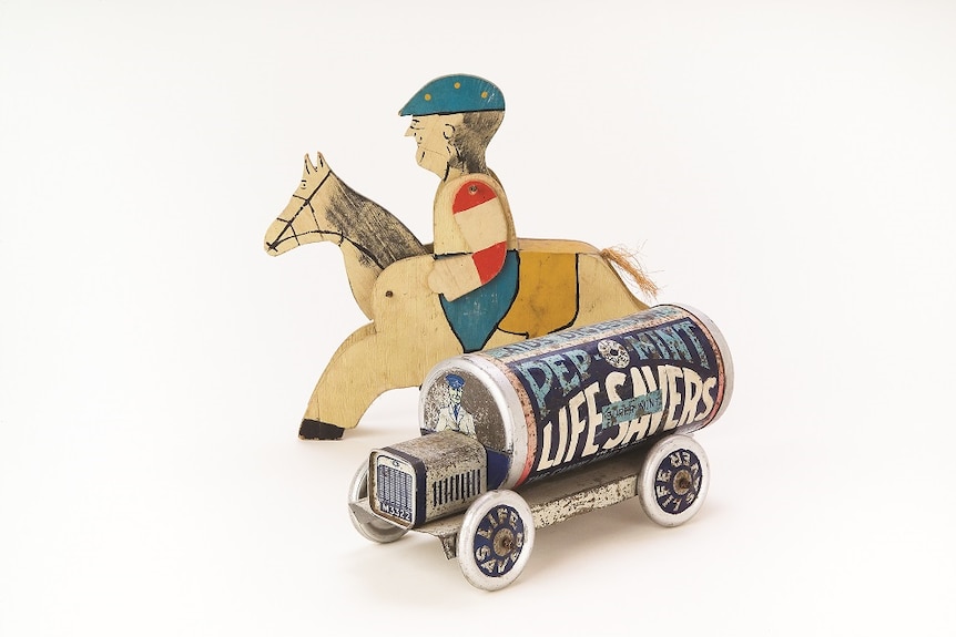 An old tin toy truck emblazoned with PEP-O-MINT LIFESAVERS and a wooden horse and jockey toy.