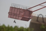 A protester swings from a piece of coal-loading machinery.