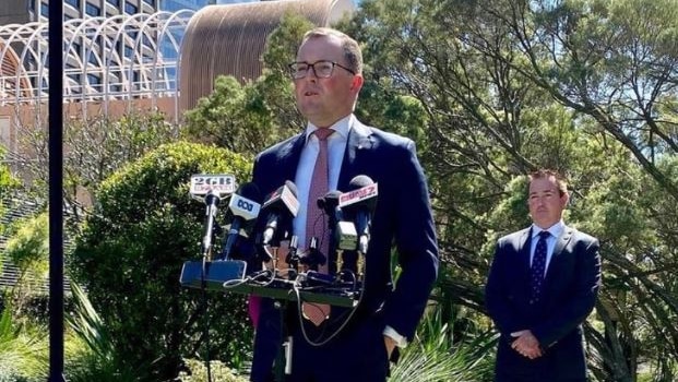 Man standing at a media podium speaking