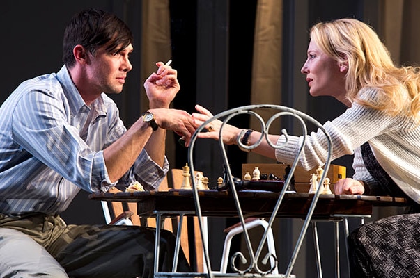 Cate Blanchett and Toby Schmitz talk while sitting at a table on stage