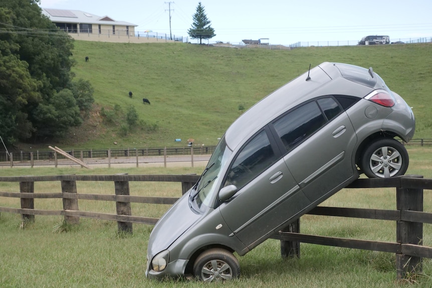 car on its side up against a gate